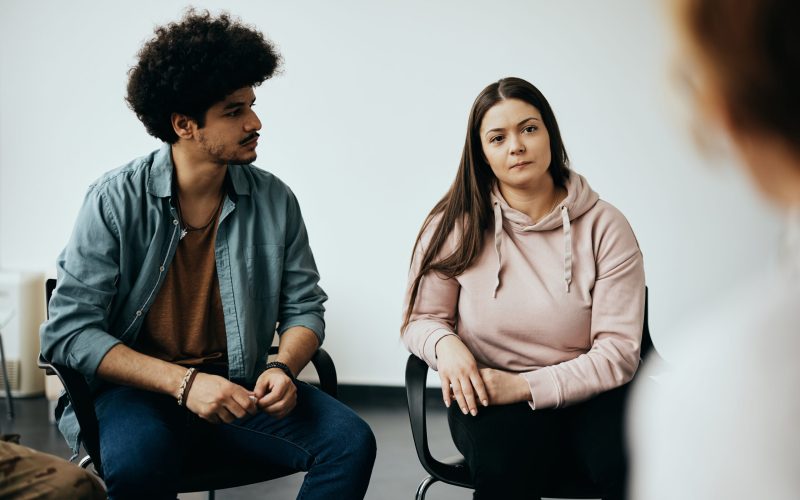 Muslim man and Caucasian woman having group therapy meeting with therapist at mental health center.